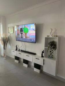 a living room with a tv on a wall at STEPS TO THE BEACH 2 Stunning condo 4 min walk to Bibijagua Beach and Catamarans in Punta Cana