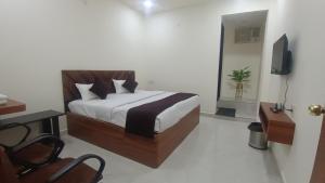 a bedroom with a bed and a desk and a tv at Hotel Venus in Jabalpur