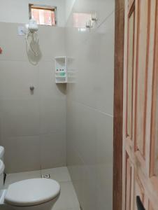 a white bathroom with a toilet and a window at Pousada Kaa - Natureza e Sossego em Itacaré in Itacaré
