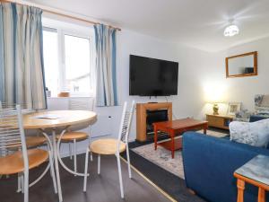 a living room with a table and a blue couch at Seaside Apartment in Looe +9 photos