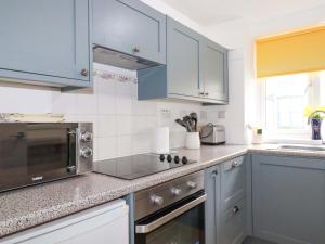 a kitchen with blue cabinets and a sink at Seaside Apartment in Looe