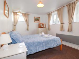 a bedroom with a bed with a blue comforter at Seaside Apartment in Looe