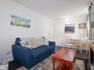 a living room with a blue couch and a table at Seaside Apartment in Looe