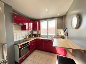 a kitchen with red cabinets and a wooden counter top at Le Robespierre - Parking privé - 5min gare in Reims