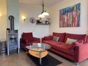 a living room with a red couch and a glass table at Ferienhaus in Lindern mit Garten & Terrasse in Werlte