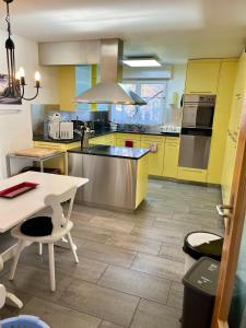 a large kitchen with yellow cabinets and a table at Grosse Ferienwohnung ideal für Gruppen, nähe Thun und Interlaken in Steffisburg