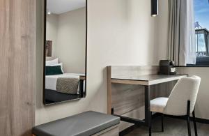 a room with a desk and a bed and a mirror at Leonardo Hotel Vienna City West in Vienna +28 photos