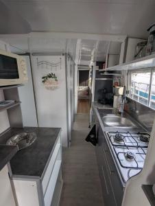 a small kitchen with a stove and a sink at Péniche Logement privé 2 chambres in Montech +1 photo