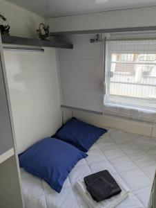 a small room with a bed and two blue pillows at Péniche Logement privé 2 chambres in Montech