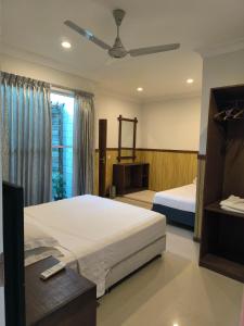 a bedroom with two beds and a ceiling fan at Ras Rana Lodge in Rasdhoo +193 photos