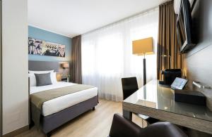 a hotel room with a bed and a desk at Leonardo Hotel Nürnberg in Nuremberg