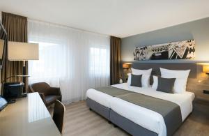 a hotel room with a large bed and a desk at Leonardo Hotel Nürnberg in Nuremberg