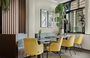 a dining room with two tables and yellow chairs at Leonardo Hotel Vienna City West in Vienna