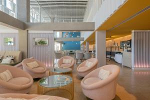 a lobby with pink chairs and tables and a kitchen at Leonardo Boutique Hotel Mallorca Port Portals - Adults only in Portals Nous
