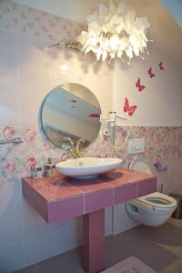 ein Badezimmer mit einem Waschbecken, einem Spiegel und einem WC in der Unterkunft Pensiunea "La Nasu" in Fîntînele