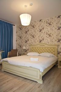 1 dormitorio con 1 cama grande con sábanas blancas y papel pintado con motivos florales en Pensiunea "La Nasu", en Fîntînele
