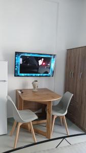 a wooden table with two chairs and a tv on a wall at Афіни Лофт in Piraeus