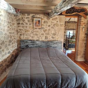 a bedroom with a large bed in a stone wall at Gite l'Etape in Vallon-Pont-dʼArc