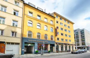 a yellow building on a street with cars parked in front at Leonardo Boutique Hotel Munich in Munich