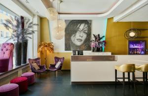 a lobby with purple chairs and a bar with a picture on the wall at Leonardo Boutique Hotel Munich in Munich