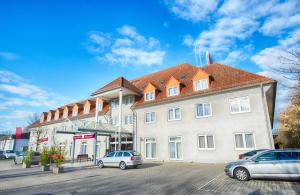 a large building with cars parked in front of it at Leonardo Hotel Mannheim-Ladenburg in Ladenburg