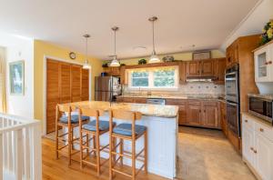 a kitchen with wooden cabinets and a island with bar stools at Pappia - Duck, Sanderling, Oceanside, 150 Yards to Beach, on Lake, Community Pool in Duck