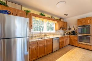 a kitchen with wooden cabinets and a stainless steel refrigerator at Pappia - Duck, Sanderling, Oceanside, 150 Yards to Beach, on Lake, Community Pool in Duck