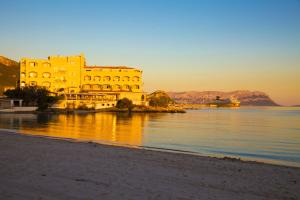 a yellow building on the shore of a body of water at Smeralda Apartment - Golfo Aranci in Golfo Aranci +25 photos