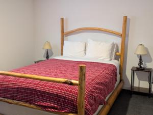 a bedroom with a wooden bed with a red blanket at Twin Peaks Hotel Cabins in Valemount