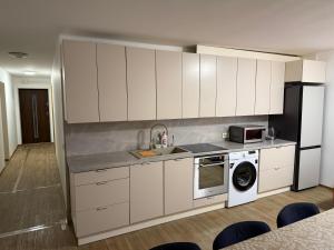 a kitchen with white cabinets and a sink and a microwave at SALGIRDO svečių namai in Kelmė