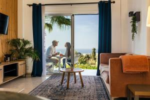 a man and a woman sitting at a table in a living room at Two Bedroom Sea View Townhouse-Villa Libellula in Khlorakas