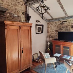 a living room with a large wooden cabinet and a tv at Gite l'Etape in Vallon-Pont-dʼArc