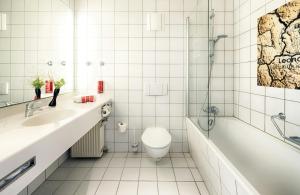 a bathroom with a tub and a toilet and a sink at Leonardo Boutique Hotel Berlin City South in Berlin +25 photos