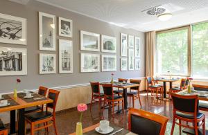 a restaurant with tables and chairs and pictures on the wall at Leonardo Hotel Berlin KU'DAMM in Berlin +16 photos