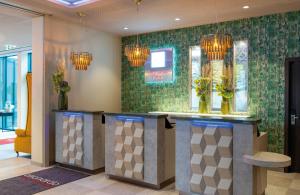 a lobby with a bar with flowers and chandeliers at Leonardo Hotel Augsburg in Augsburg +75 photos