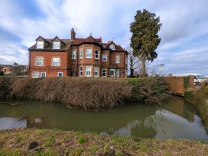 a large brick building on a hill next to a body of water at Lakeside Oxford Hotel in Oxford
