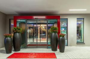 three large vases with flowers in front of a building at Leonardo Hotel Augsburg in Augsburg