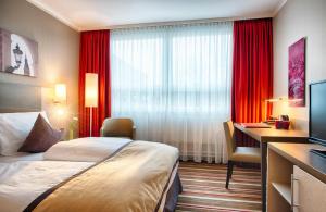 a hotel room with a bed and a desk and a television at Leonardo Hotel Hamburg City Nord in Hamburg