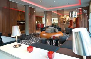 a hotel lobby with a couch and tables and lamps at Leonardo Hotel Völklingen-Saarbrücken in Völklingen
