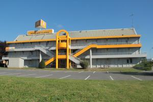 a large building with a yellow structure in a parking lot at Premiere Classe Soissons in Soissons