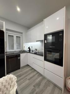 a kitchen with white cabinets and black appliances at Feeling Porto House in Porto