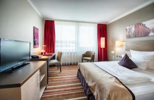 a hotel room with a bed and a flat screen tv at Leonardo Hotel Hamburg City Nord in Hamburg