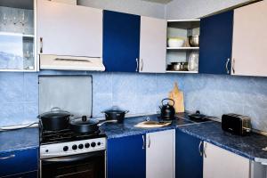 a kitchen with blue and white cabinets with pots on the stove at Gudauri Deka House, Balcony & Mountain Views in Gudauri