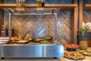 a buffet with many plates of food on a counter at Leonardo Hotel Breda City Center in Breda
