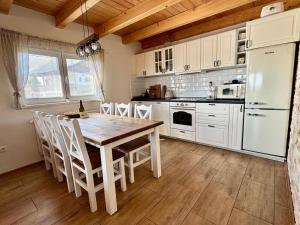 a kitchen with a wooden table and white appliances at Wellness chata Kozička in Klokočov