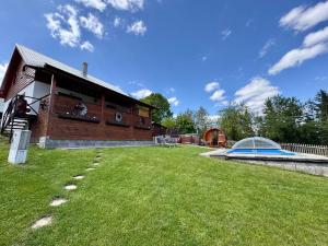 a building with a grass yard in front of a house at Wellness chata Kozička in Klokočov