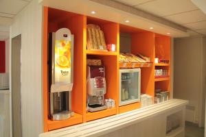 - une cuisine avec une armoire orange et une machine à café dans l'établissement Premiere Classe Soissons, à Soissons