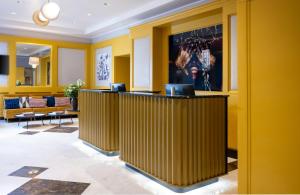 Die Lobby eines Hotels mit gelben Wänden und Tischen in der Unterkunft Leonardo Boutique Hotel Rome Monti in Rom