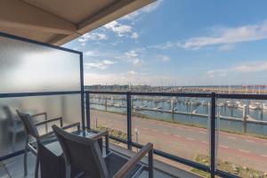 a balcony with chairs and a view of a harbor at Leonardo Hotel IJmuiden Seaport Beach in IJmuiden