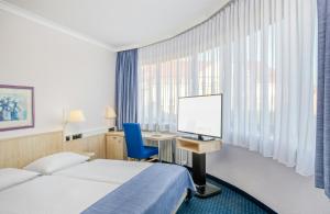 a hotel room with a bed and a desk with a computer at Hotel Erfurt City Center by Leonardo Hotels in Erfurt